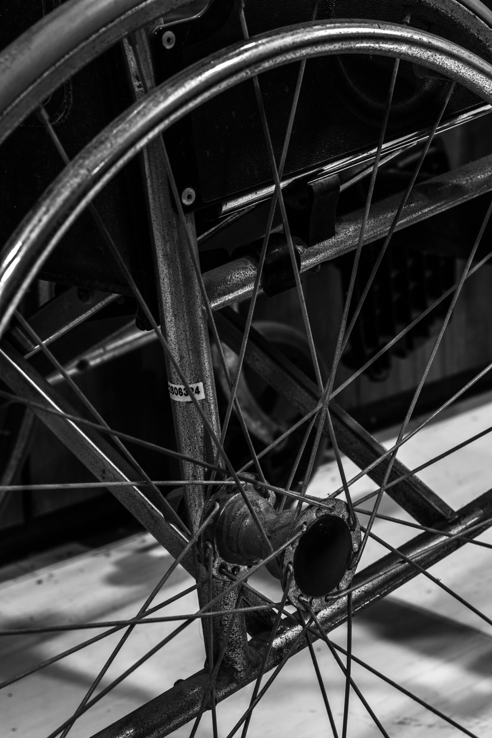 Detailed black and white close-up showing the wheel and spokes of a wheelchair.