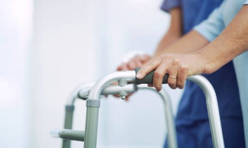 Shot of an unrecognizable senior woman being assisted to walk using a walker by a nurse at a retirement home